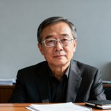 华润置地资产管理部张总经理的近照，一位五十岁左右的商务男士，身着深色西装佩戴银色框架眼镜，神态沉稳专业